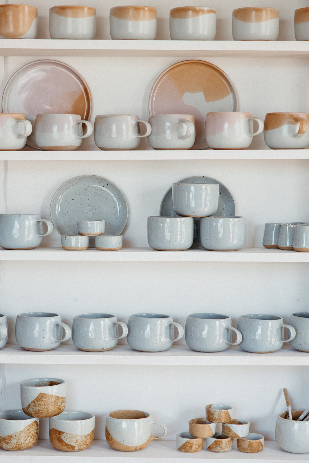 Shelves filled with handmade coffee and tea cups at Palinopsia Ceramics in Newcastle