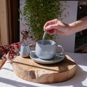 Hand stirring tea in a handmade mug, basking in the sun by Palinopsia Ceramics