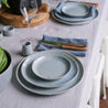 Set dinner table by Palinopsia Ceramics with a three piece dinner set, blue table napkins and french cutlery 