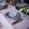 Beautiful table setting by Palinopsia Ceramics with stoneware dinner set, grey linen tablecloth and fresh vegetables 