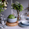 Blue grey dinnerware setting by Palinopsia Ceramics with fresh flowers, watermelon and a grey tablecloth 