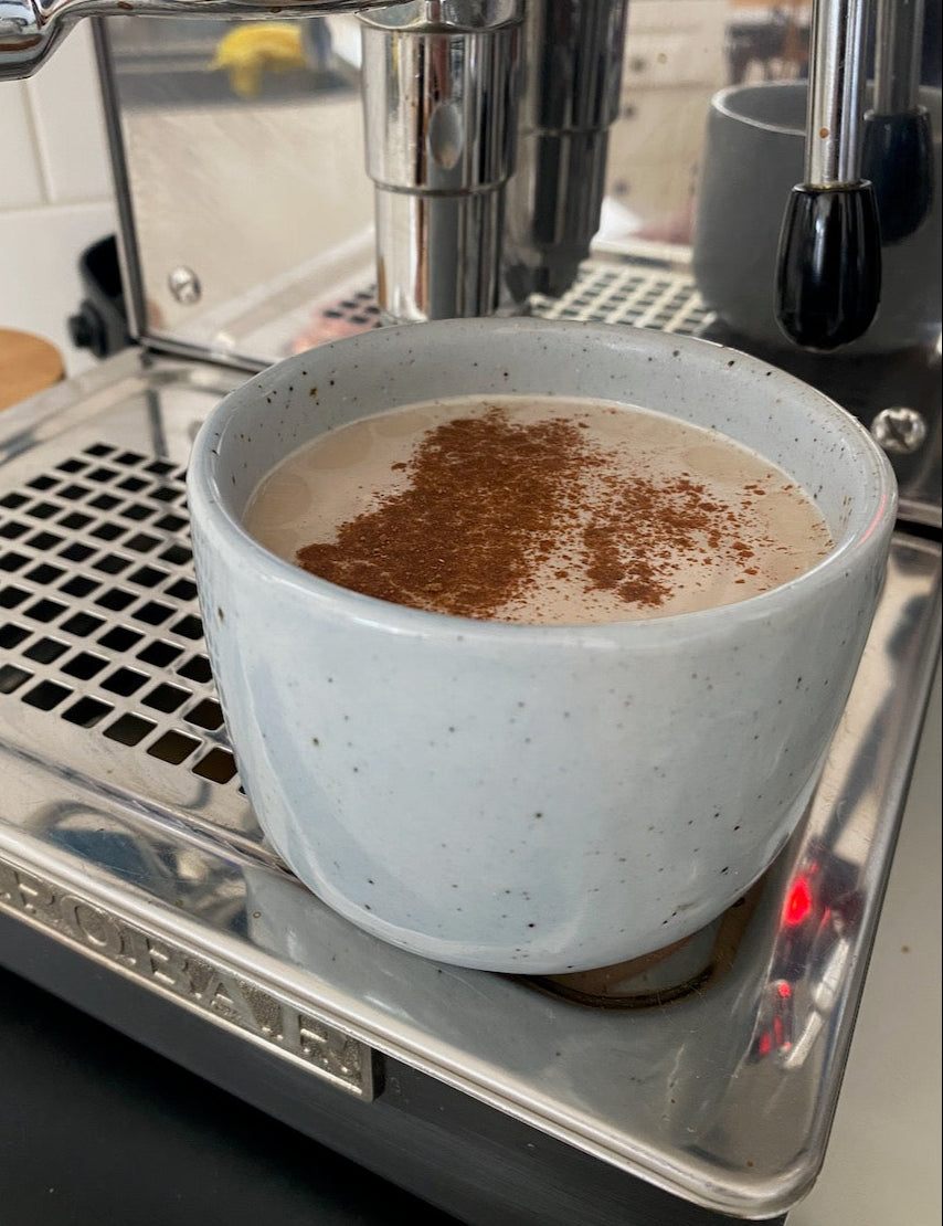 A blue coffee cup placed on a  coffee machine  at Palinopsia Ceramics