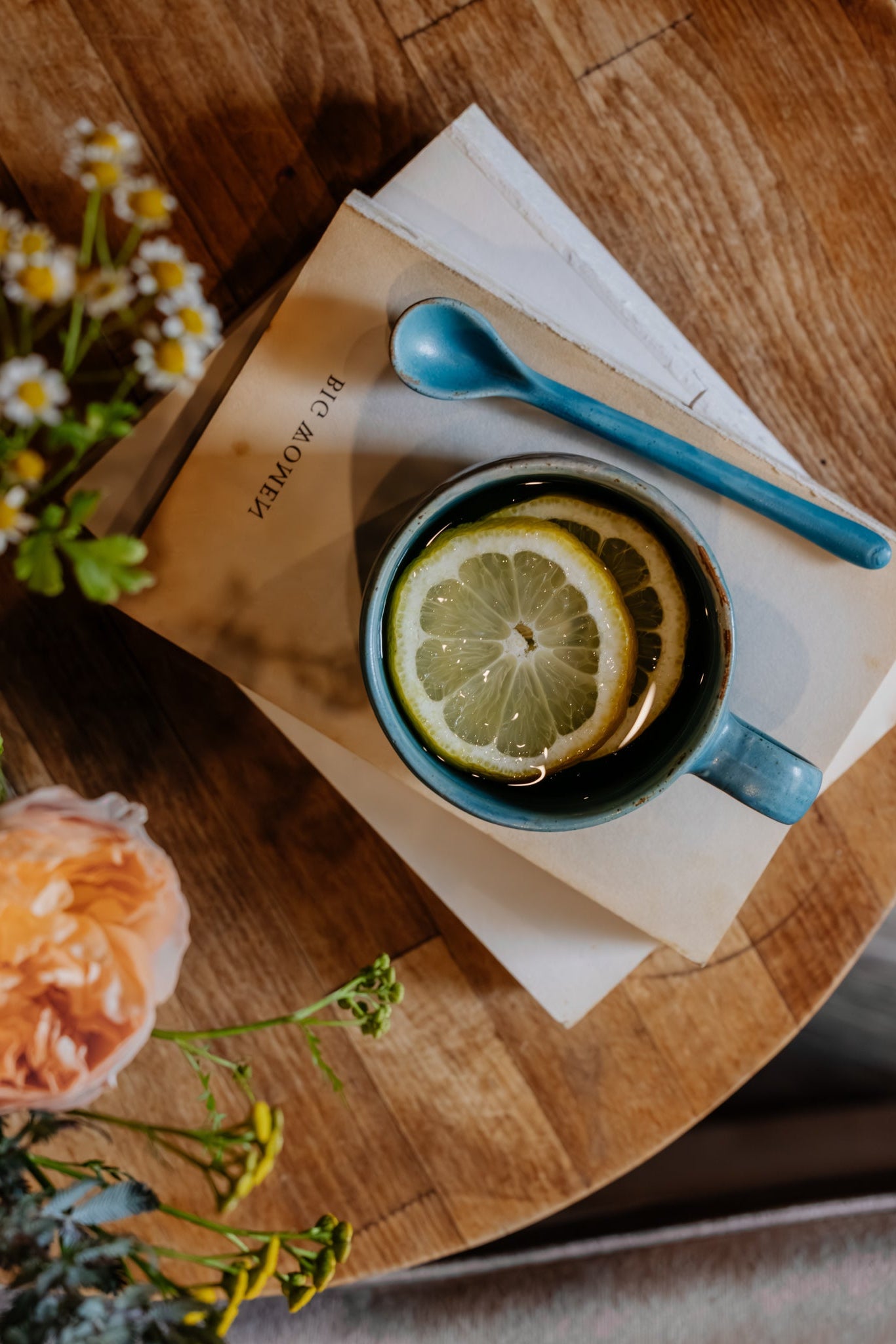 Teal green mug with lemon tea on a stack of books
