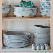 Ceramics serving accessories stacked on a shelf by Palinopsia