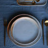 Dinner plate and lunch plate in a rustic blue colour palette on a linen blue tablecloth and gold cutlery