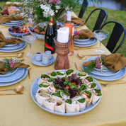 Large round serving platter plate in blue by Palinopsia Ceramics on yellow linen tablecloth