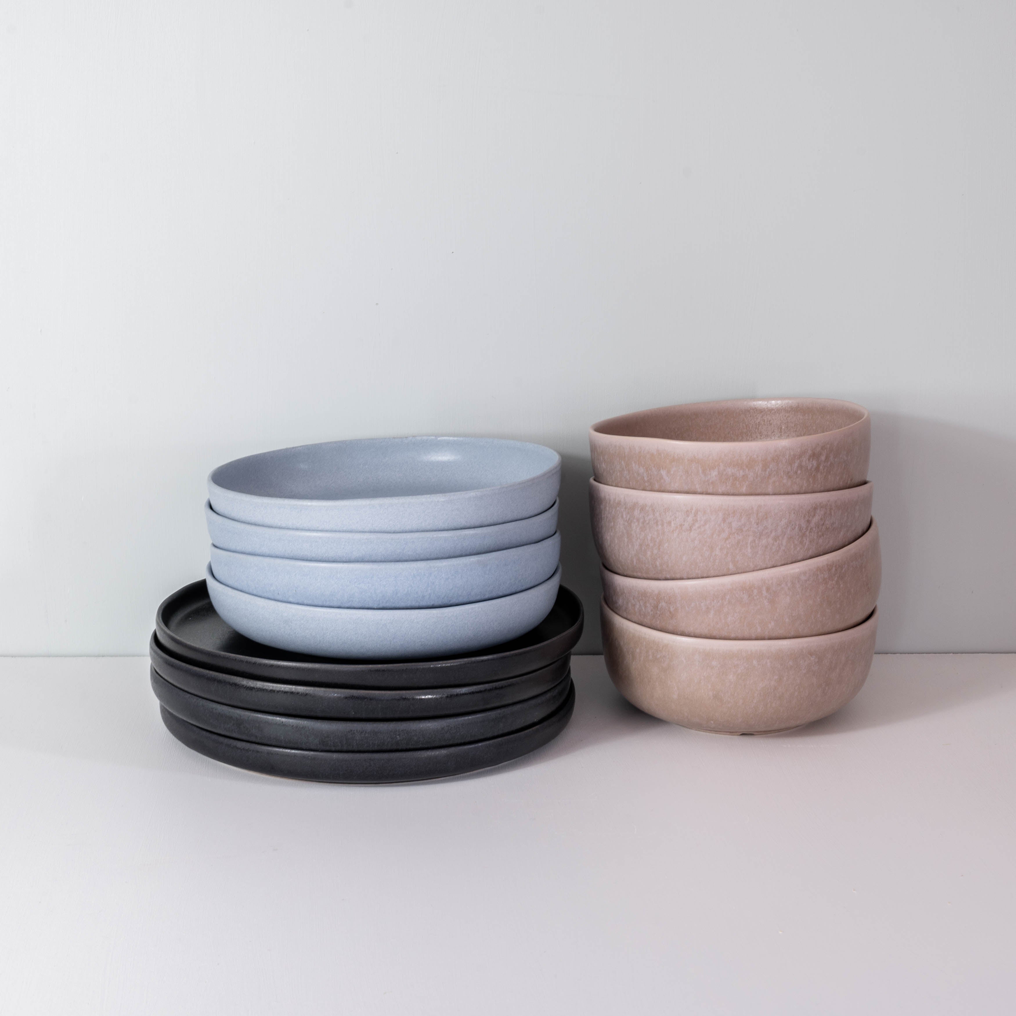 Side view of a stack of handmade dinner set by Palinopsia Ceramics in block colours of black Ink, powder blue and mushroom grey in Newcastle Australia