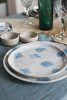 Handmade ceramic plates on a  blue pure linen tablecloth by Palinopsia Ceramics  