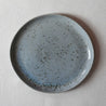 Bird's-eye view of a handmade dinner plate with organic shape in blue and grey with speckles by Palinopsia Ceramics 