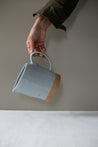 Hand holding a handmade jug with a handle in blue grey
