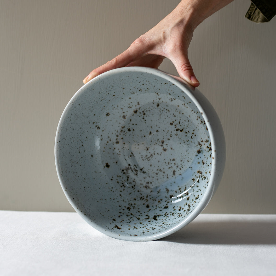 Hand holding a handmade fruit bowl in blue grey with speckles by Palinopsia Ceramics