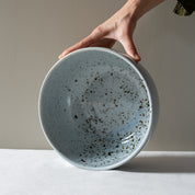 Hand holding a handmade fruit bowl in blue grey with speckles by Palinopsia Ceramics