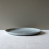 Side view of a large round handmade dinner plate 