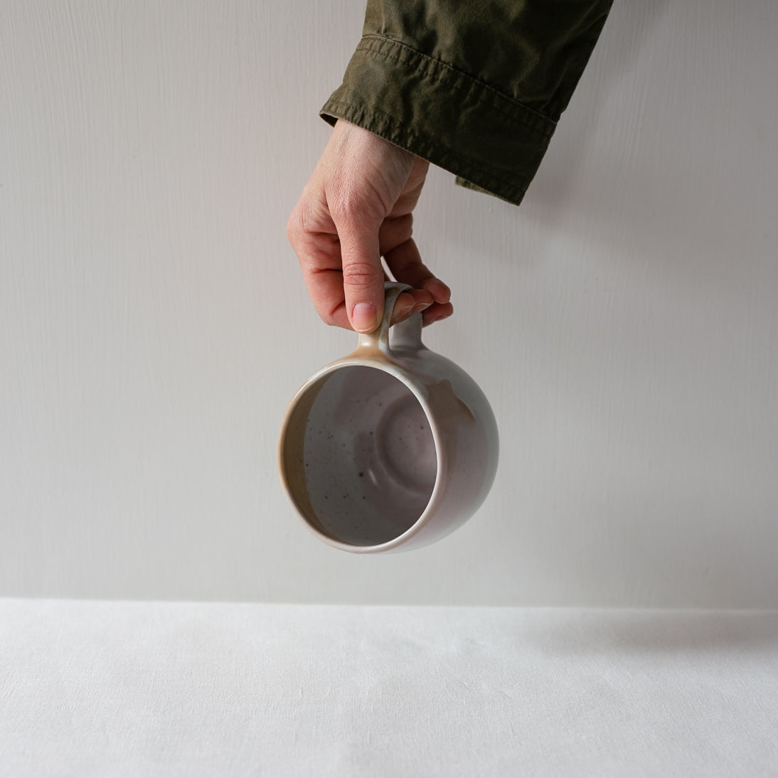 Hand holding a single handmade stoneware mug by Palinopsia Ceramics