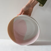 Hand holding a handmade fruit bowl in colourful pink, brown and white playful colours by Palinopsia Ceramics