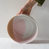 Hand holding a handmade fruit bowl in colourful pink, brown and white playful colours by Palinopsia Ceramics 