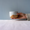 A single hand holding out a coffee cup 