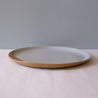 Side view of a single handmade dinner plate in browns and blues