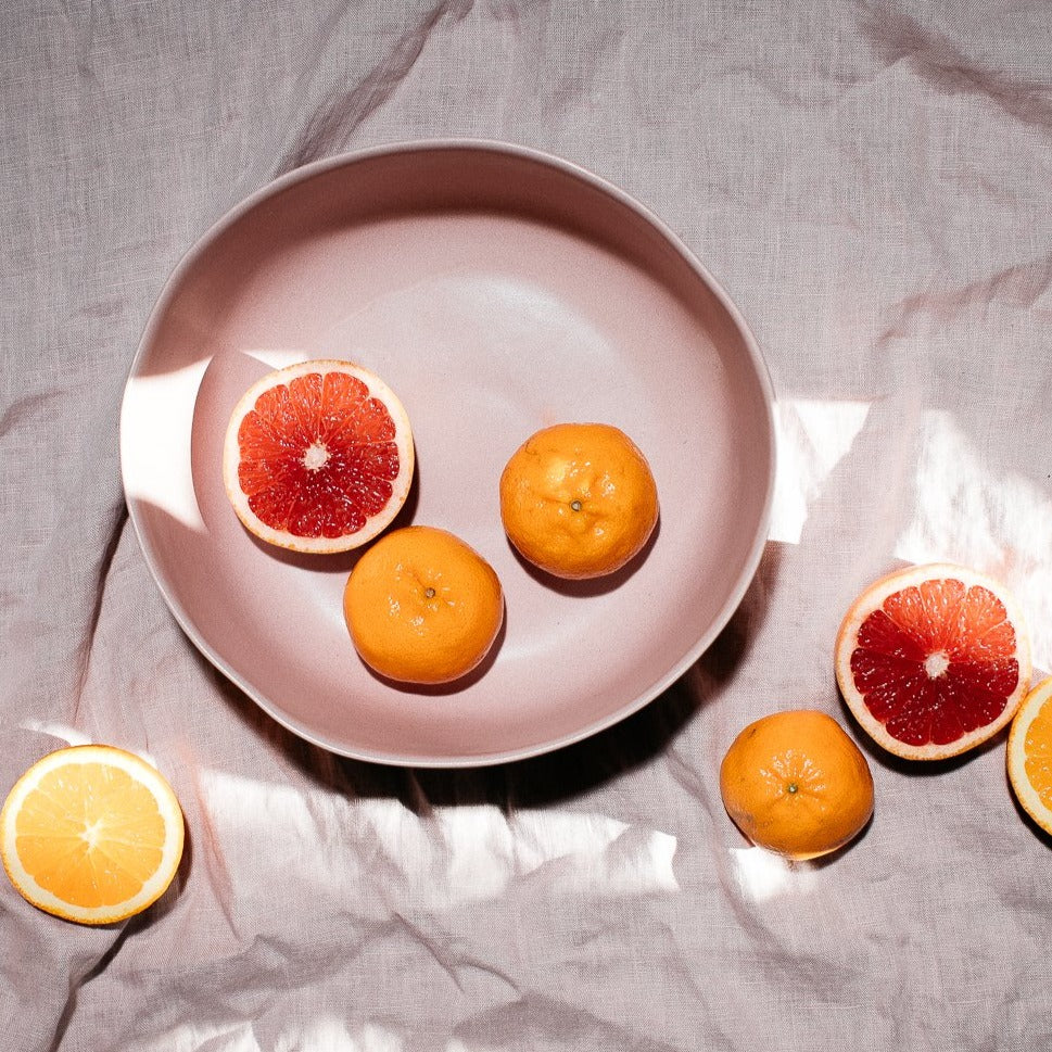 Handmade Dusty Pink Fruit bowl by Palinopsia Ceramics on a linen sheet with bright citrus in Sydney Australia