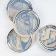 Set of four small handmade ceramic plates with a marbled clay pattern in cobalt blue, beige and cream on a white background by Palinopsia