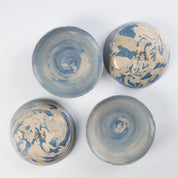 Set of four handmade ceramic bowls with a marbled clay pattern in cobalt blue, beige and cream on a white background by Palinopsia