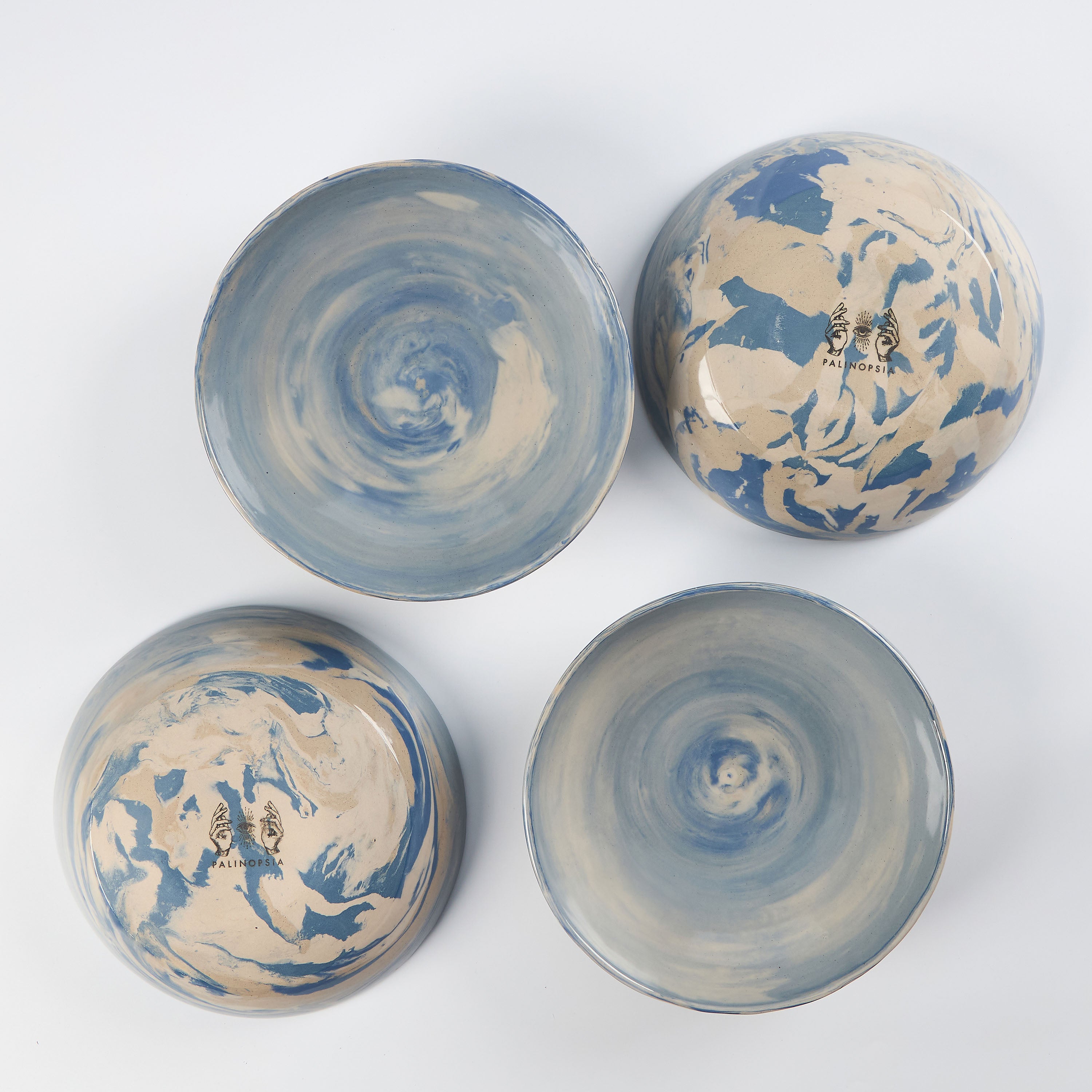 Set of four handmade ceramic bowls with a marbled clay pattern in cobalt blue, beige and cream on a white background by Palinopsia