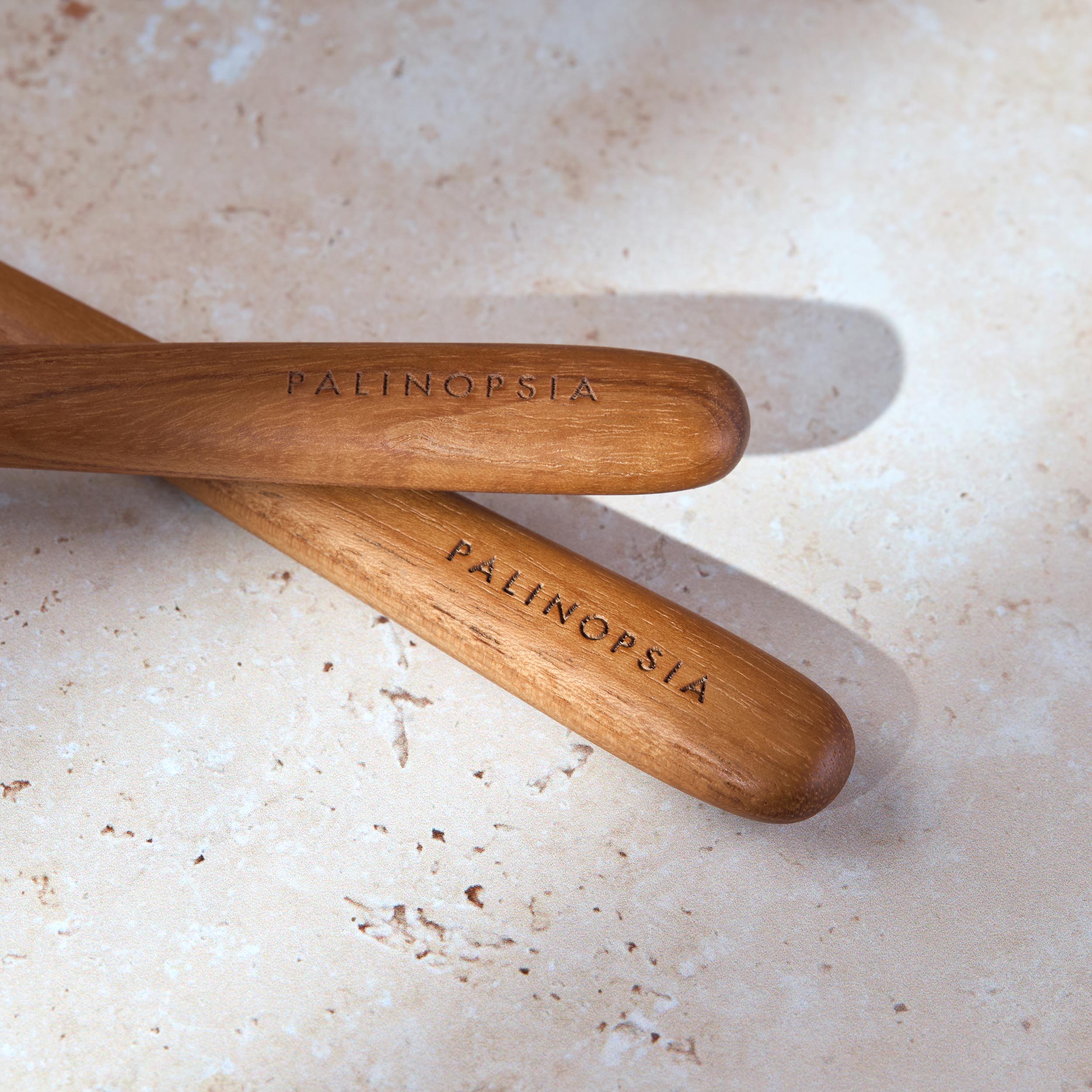 Close-up shot of the handles of retro teak wooden salad servers with Palinopsia labels on the handles.