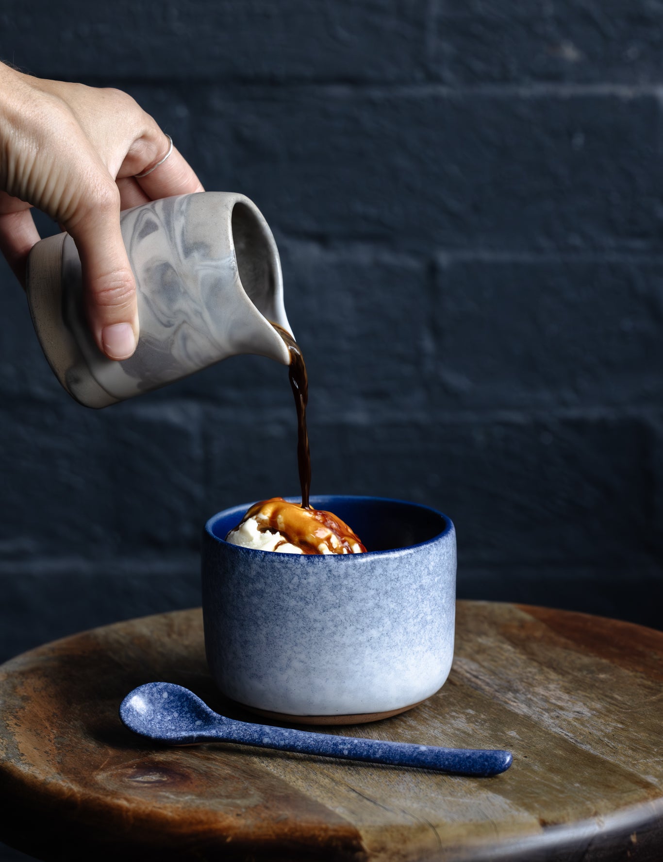 Affogato, hand pouring coffee over ice cream in a Palinopsia winter themed tumbler cup on a stool with a dark navy background of Autumn Rooms cafe