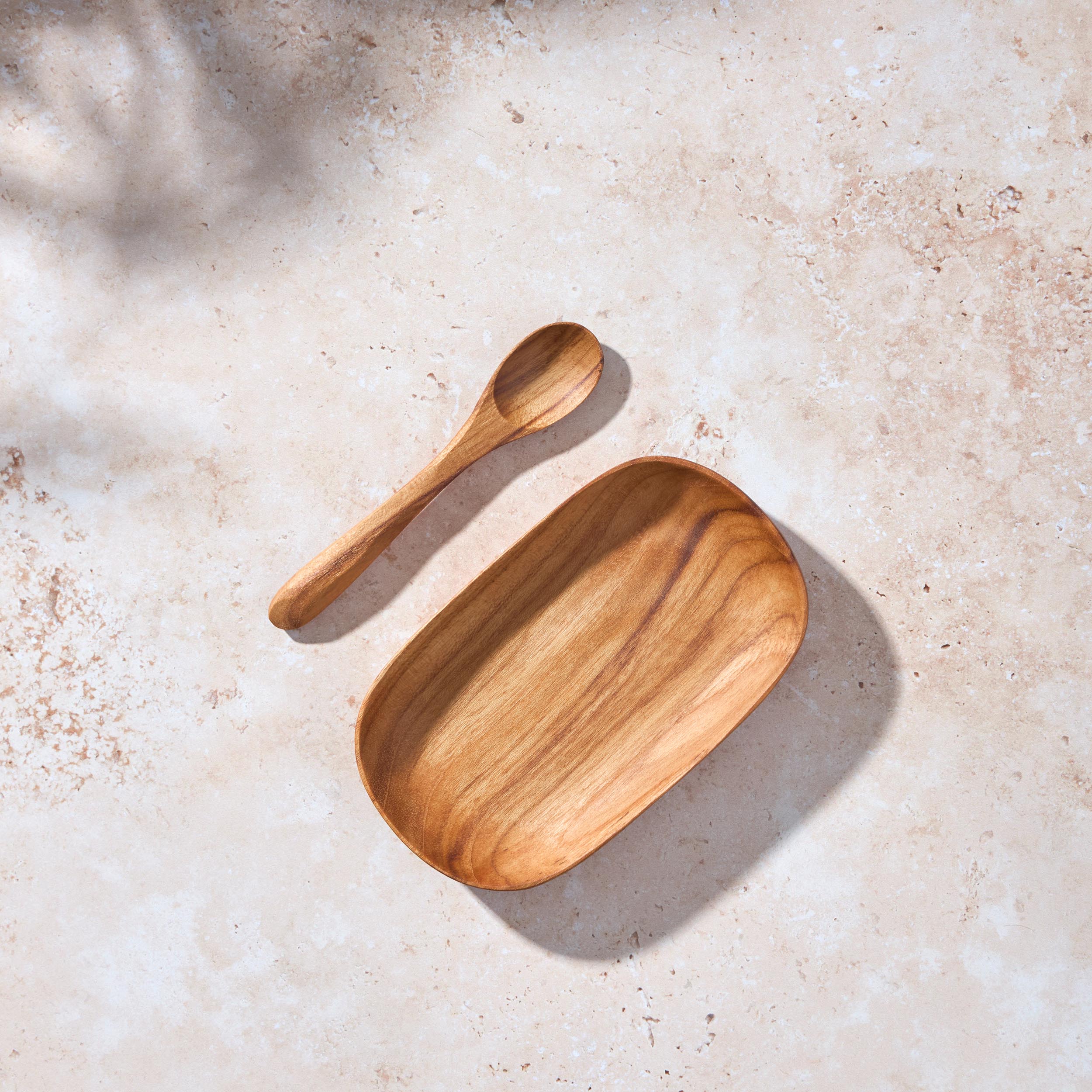 Palinopsia teak wooden plate and spoon on a textured beige surface