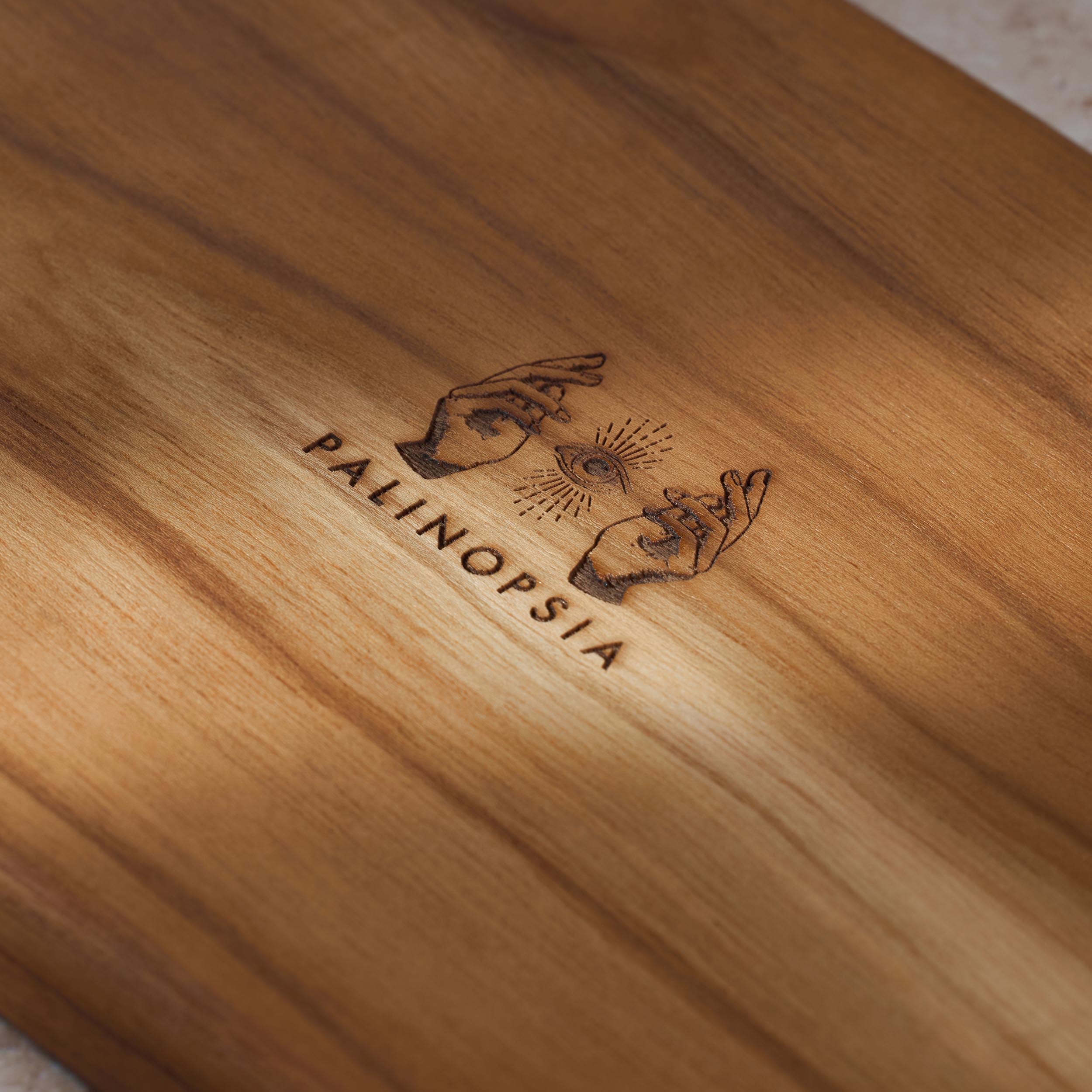 Detailed shot of a teak wooden serving platter with the Palinopsia logo on the bottom.
