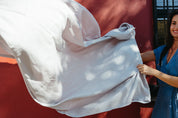 Woman in blue dress holding a light grey linen tablecloth