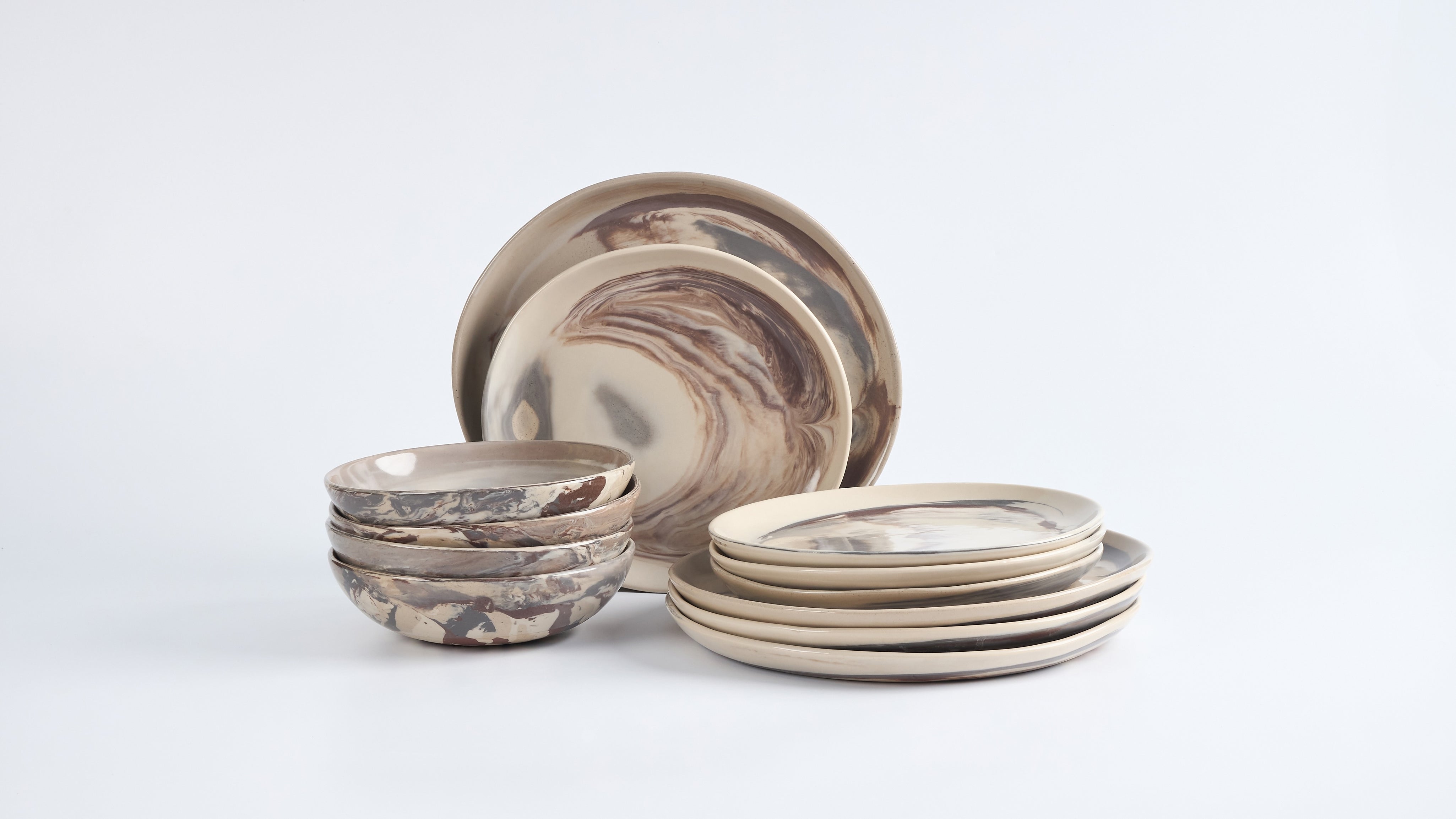 Set of handmade ceramic bowls and plates with marbled design on a white background