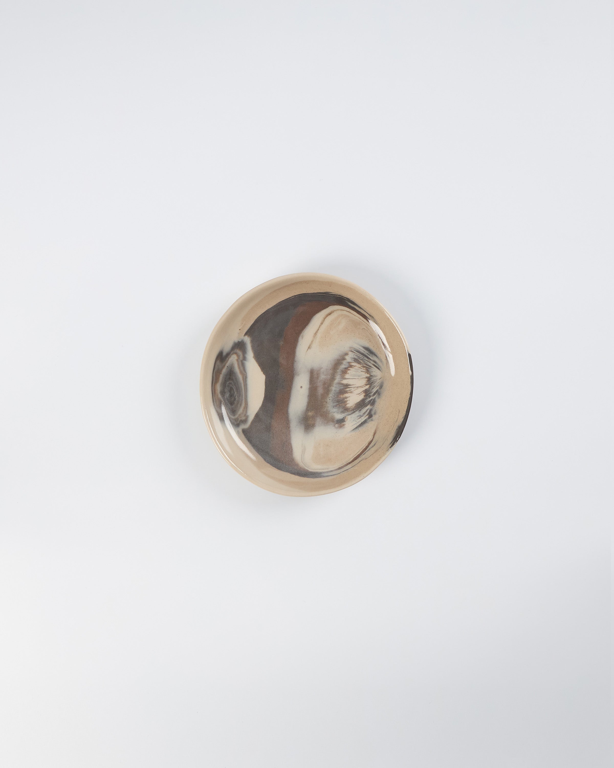 Round ceramic side plate with abstract marble design on a white background
