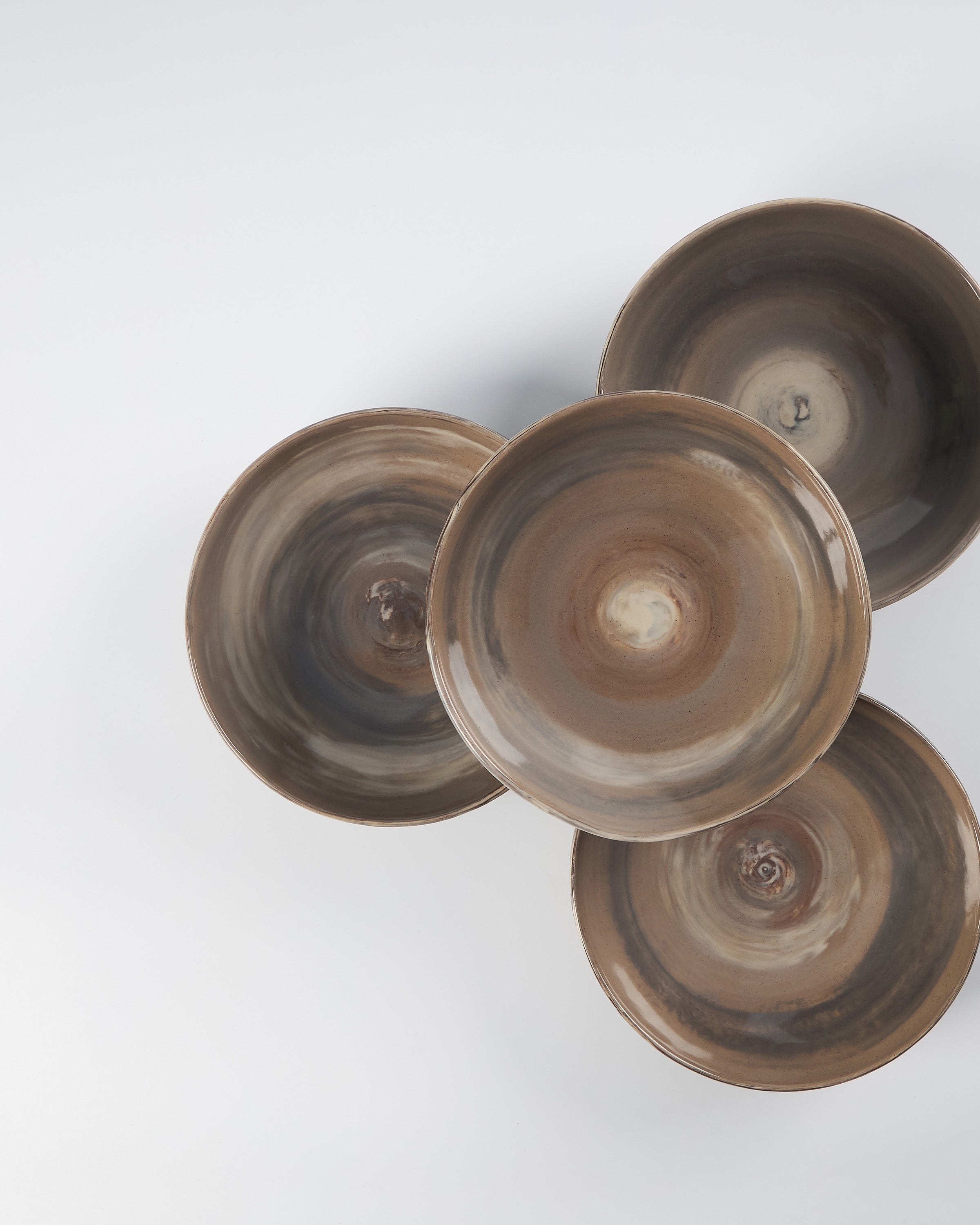 Four brown ceramic bowls on a white background birds eye
