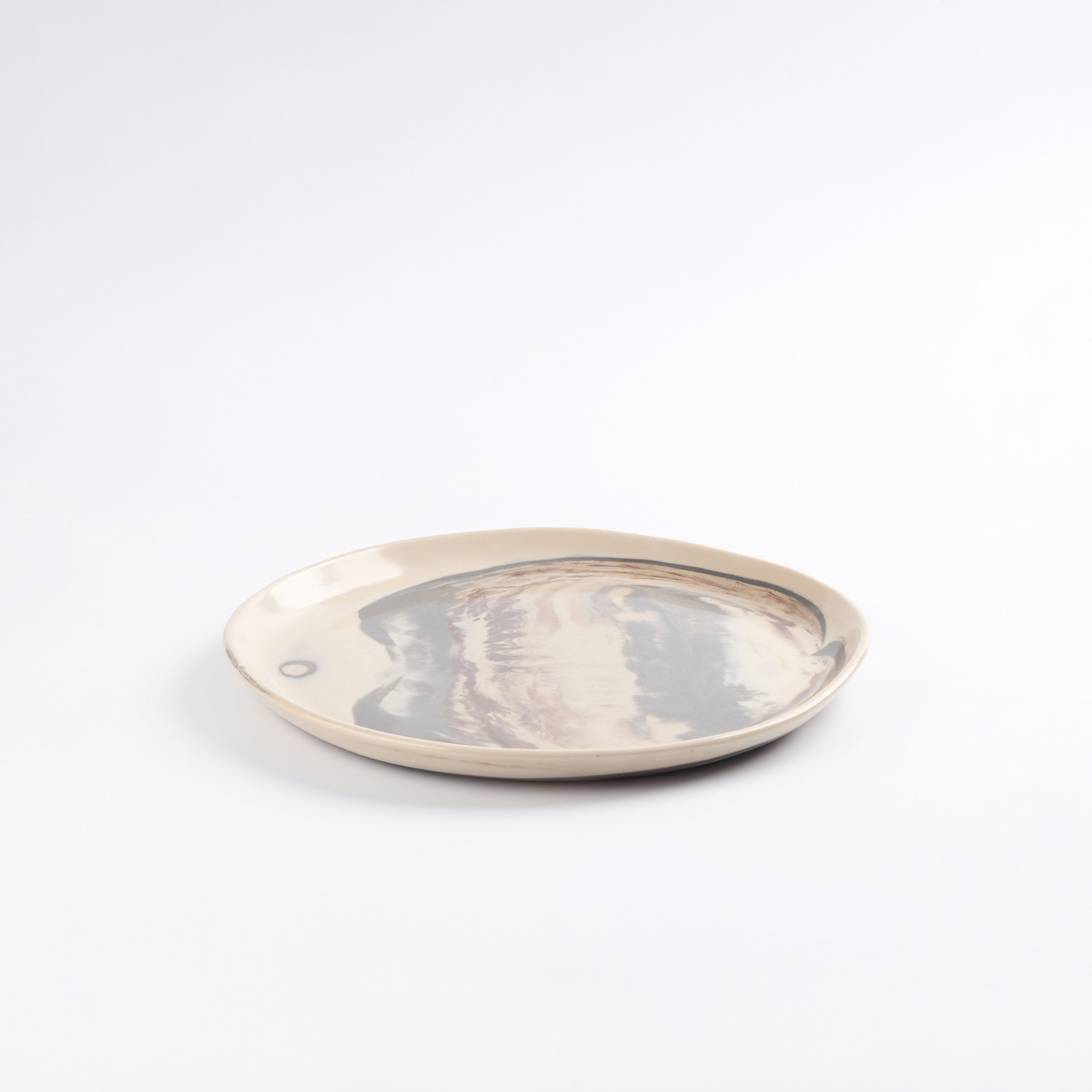 Round ceramic plate with a four colour marbled clay pattern on a white background
