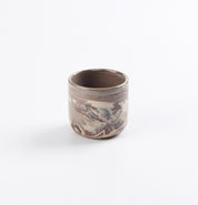 Ceramic espresso cup with four clay marbled design on a white background