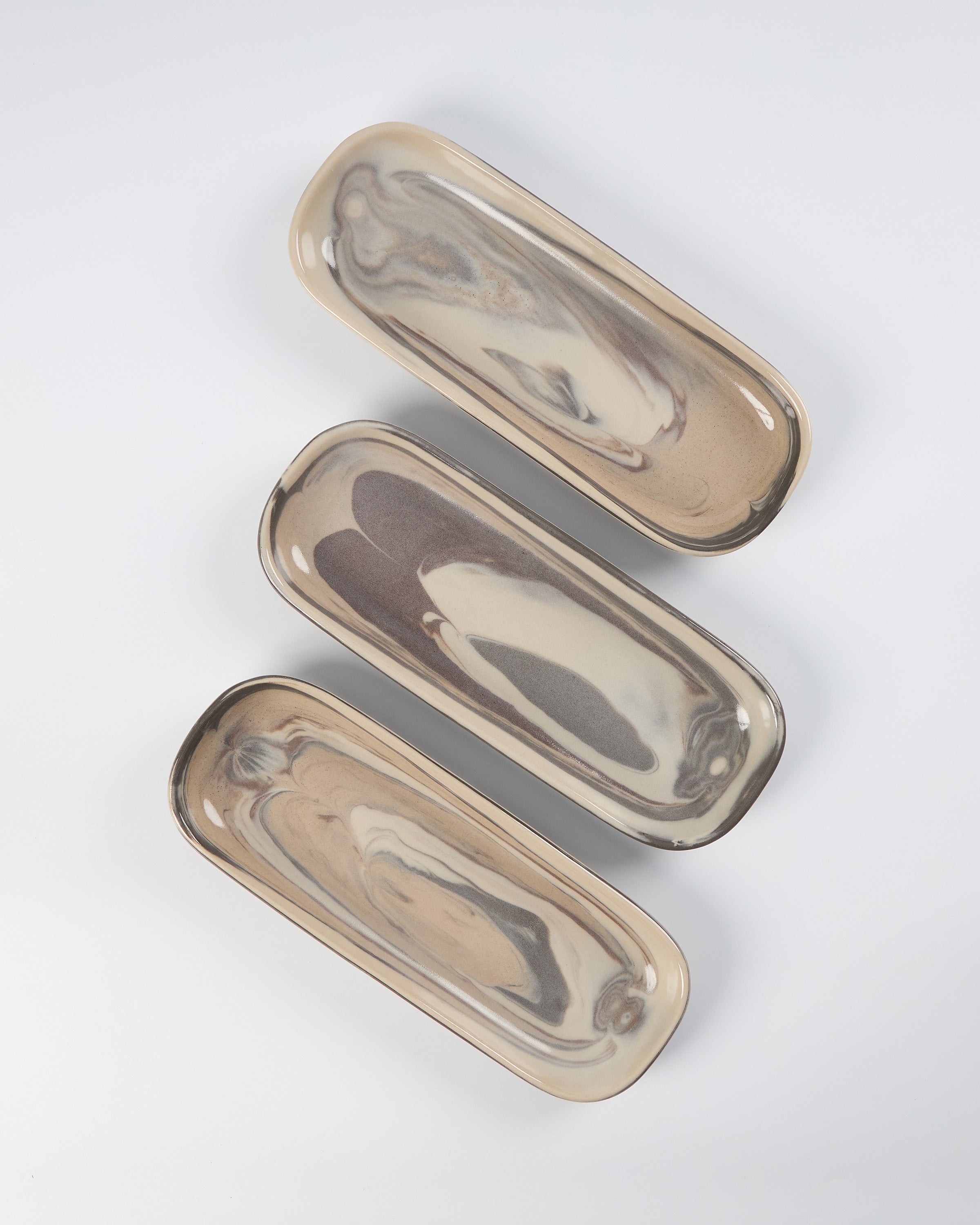 Three marbled clay ceramic oval trays on a white background