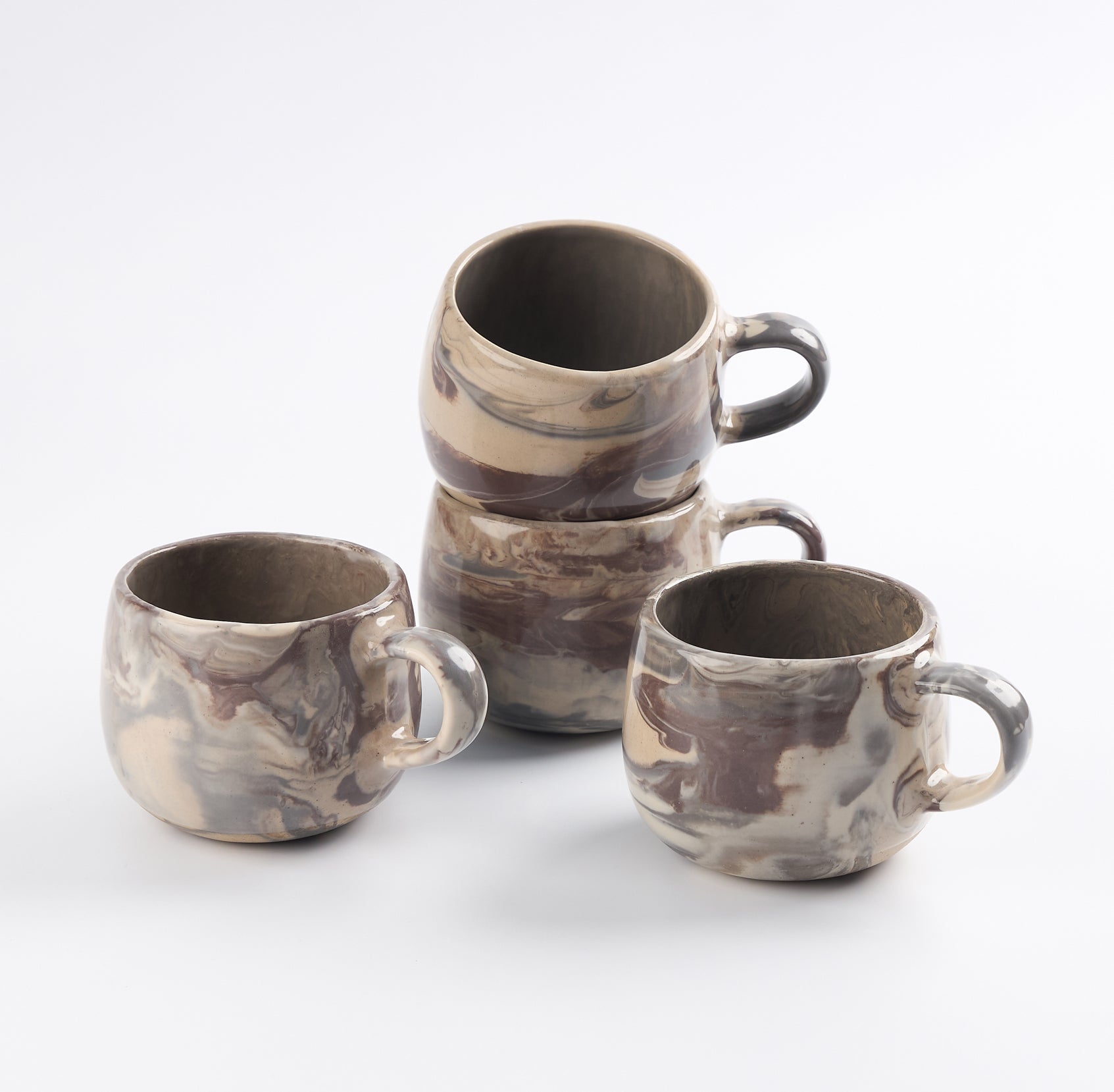 Set of four ceramic mugs with marbled design on a white background
