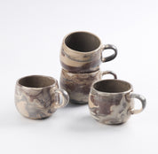 Set of four ceramic mugs with marbled design on a white background