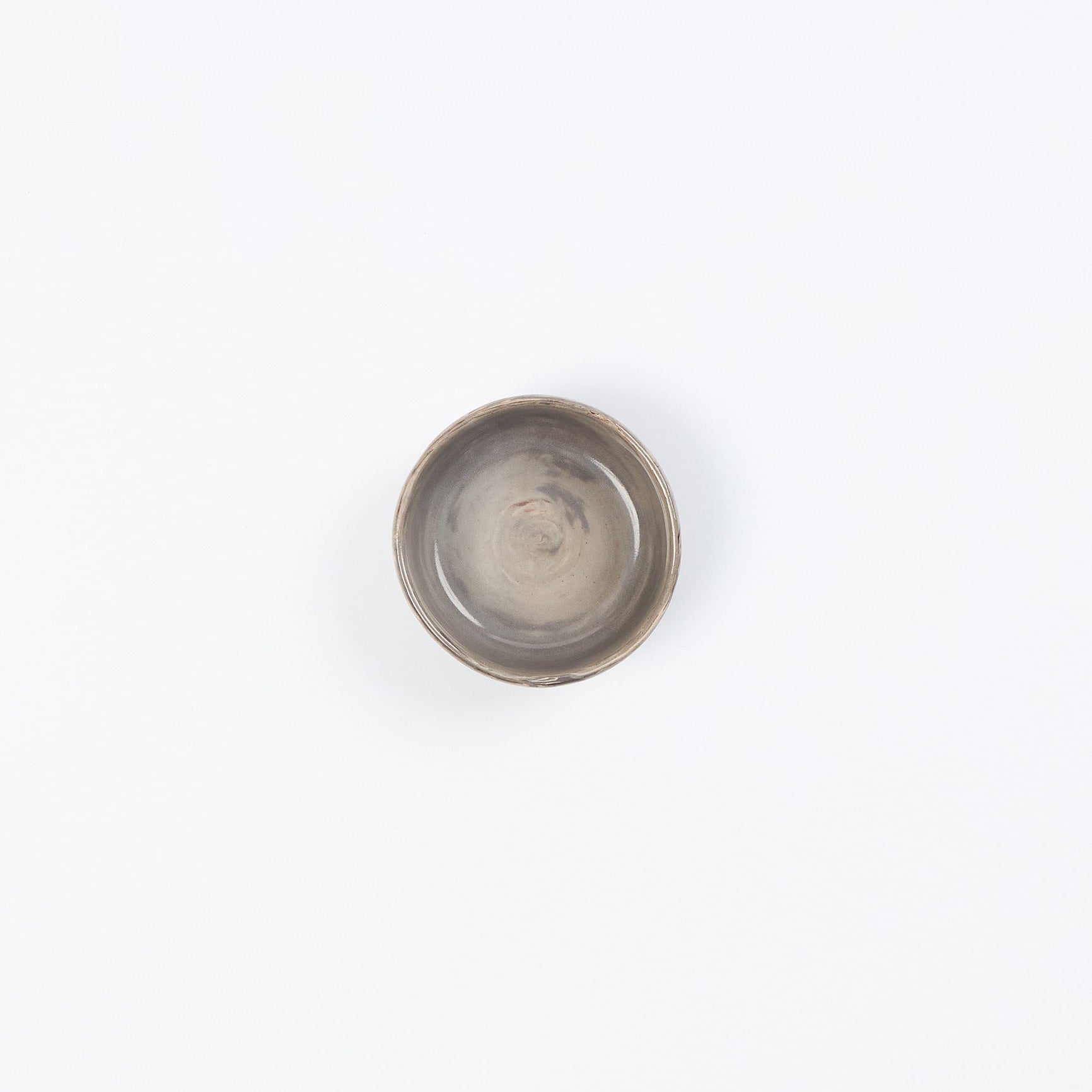 Birds eye view of a small ceramic dish in neutral tones against a white background