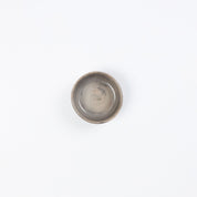 Birds eye view of a small ceramic dish in neutral tones against a white background