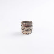 Stack of marbled ceramic small dishes with earthy tones on a white background