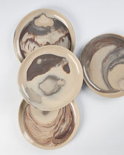 Set of four ceramic plates with marbled design on a white background