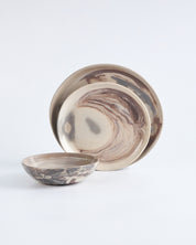 Handmade marbled ceramic dinner set with a bowl and two plates on a light grey background