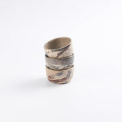 Stack of three ceramic small bowls with abstract marble patterns on a white background