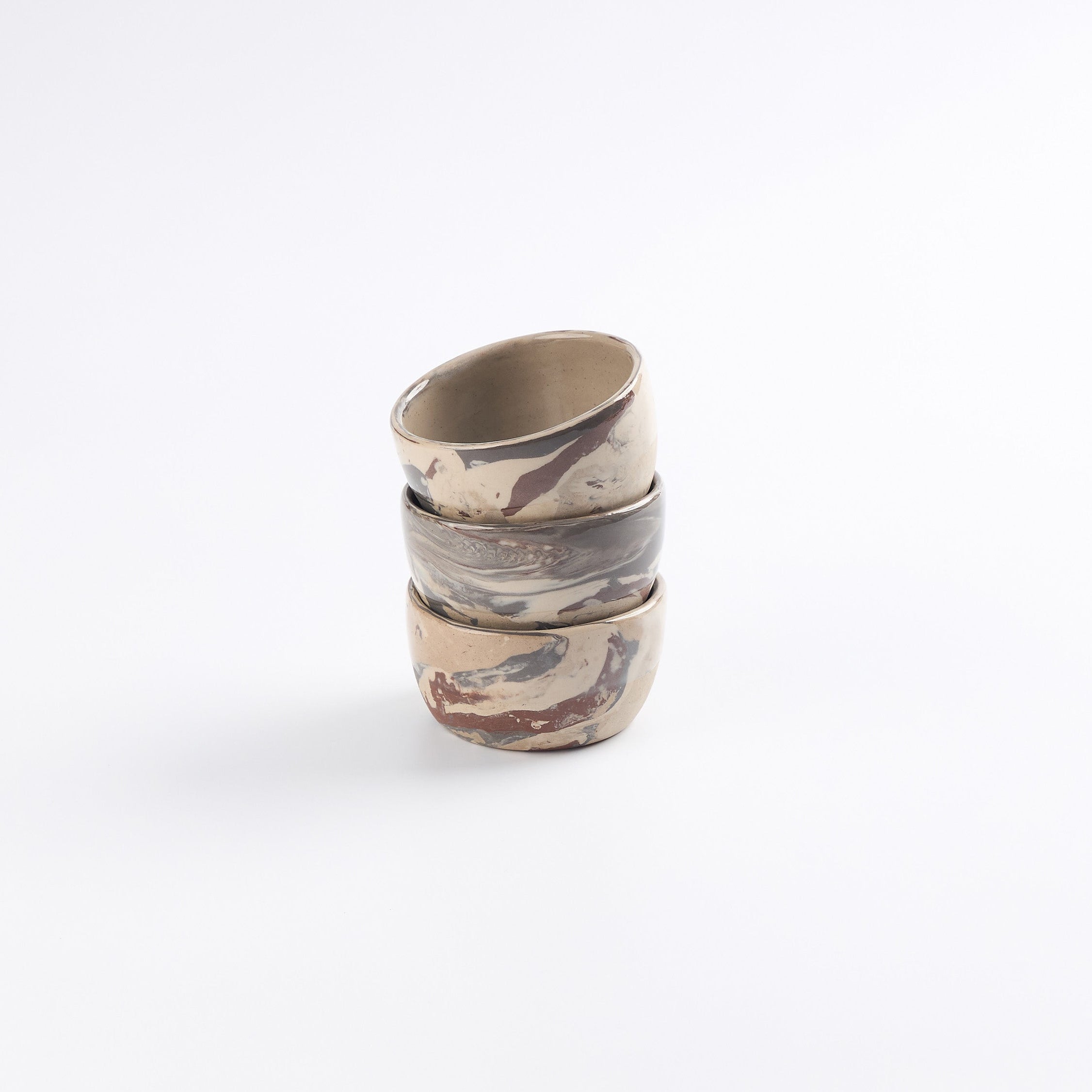 Stack of three ceramic small bowls with abstract marble patterns on a white background