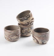 Set of four ceramic cups with marbled design on a white background