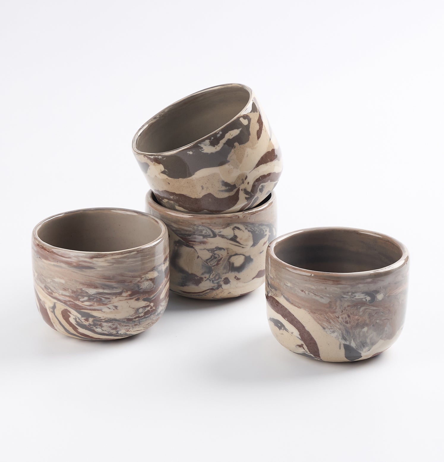 Set of four ceramic cups with marbled design on a white background