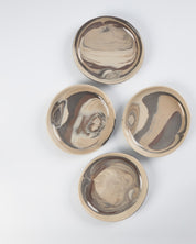 Four ceramic plates with marbled design on a white background