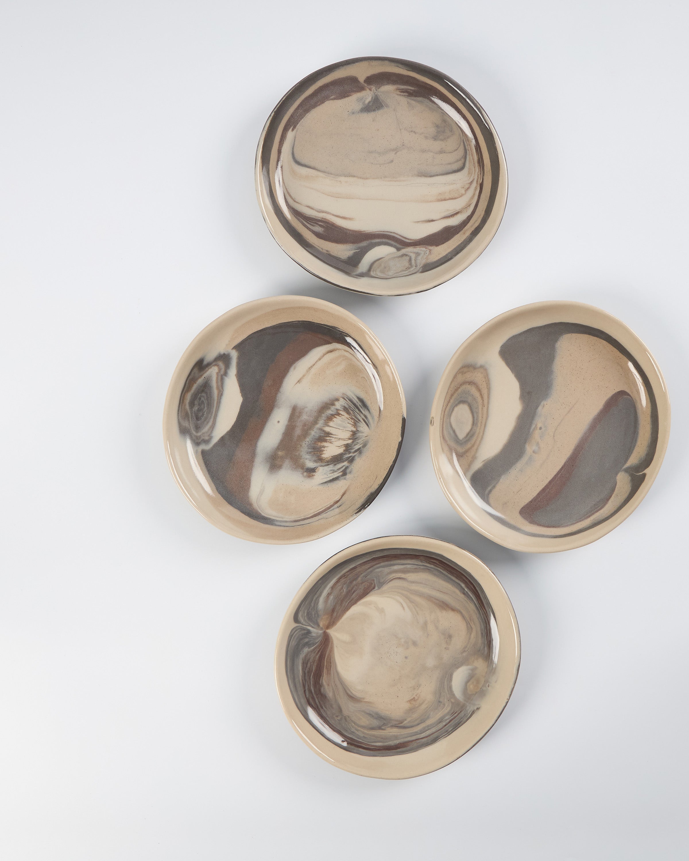 Four ceramic plates with marbled design on a white background